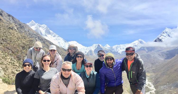Group of people posing with snow-capped mountains in the background.
