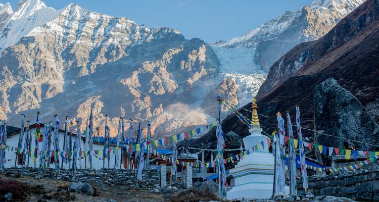 Kloster mit Gebetsfahnen vor schneebedeckten Bergen.