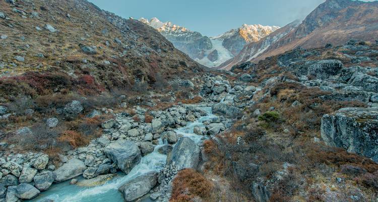Felsiges Tal mit einem fließenden Fluss und Bergkulisse.