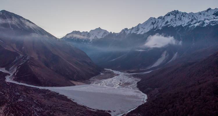 Abendblick auf ein Tal mit Fluss und hohen Berggipfeln.