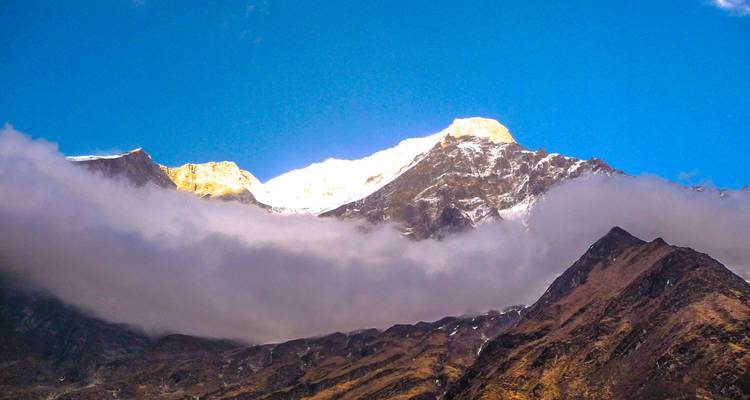 Dramatischer Berggipfel, teilweise von Wolken bedeckt.
