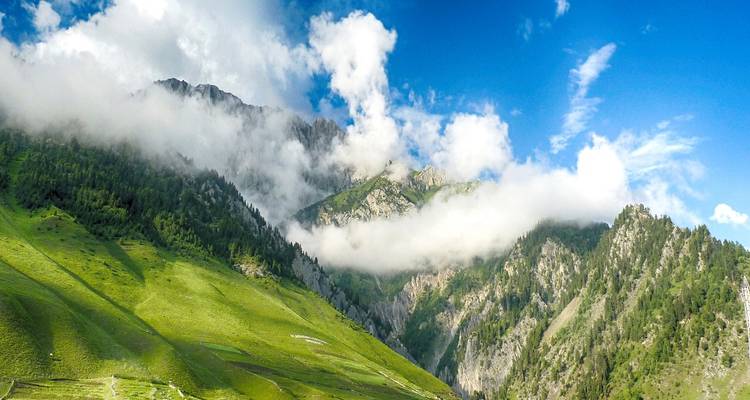 Des collines verdoyantes sous un ciel lumineux avec des formations nuageuses.