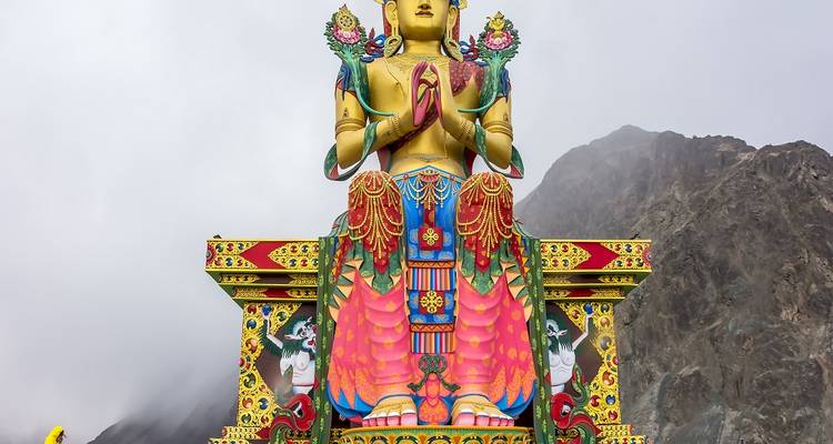 Grande statue colorée de Bouddha sur fond montagneux dans la vallée de Nubra.