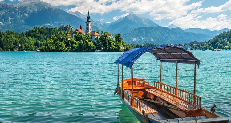 Scène idyllique au lac de Bled avec un bateau traditionnel et une église.
