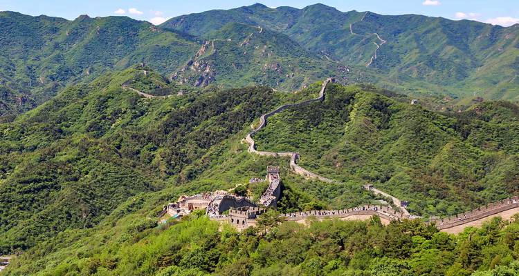 Luchtfoto van de Grote Muur van China die zich uitstrekt over weelderige groene bergen
