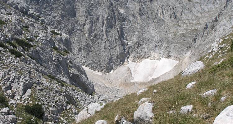 Terrain rocheux avec des plaques de neige et de l'herbe.