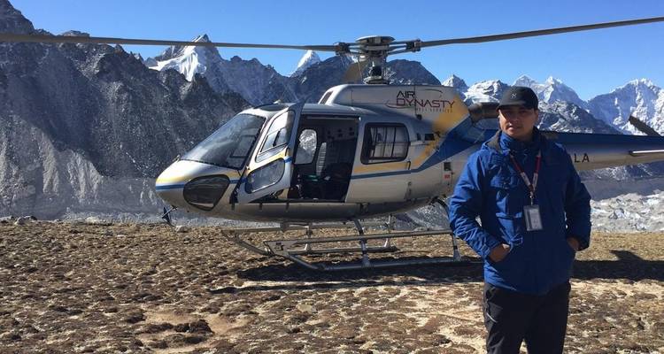 Hombre frente a un helicóptero en una ubicación montañosa.
