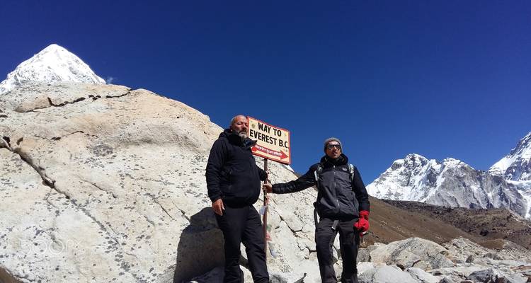Dos hombres junto a un letrero que indica hacia el Campo Base del Everest.