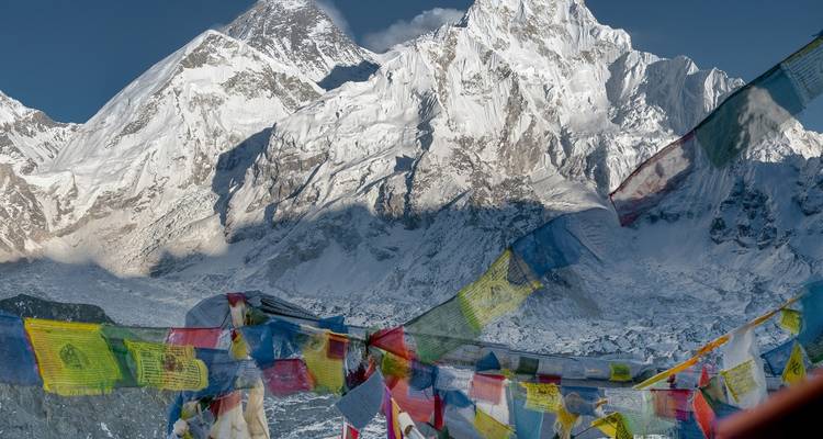Snow-capped mountains with colorful prayer flags in the foreground.