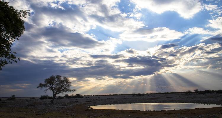Rayos de sol atravesando las nubes sobre un paisaje árido.