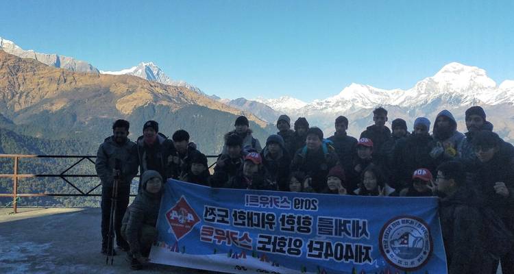 Groupe de personnes tenant une bannière avec des montagnes en arrière-plan.