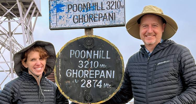 Deux personnes posant à côté d'un panneau à Poonhill.