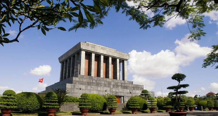 The solemn granite Ho Chi Minh Mausoleum stands amidst manicured gardens and blue skies.