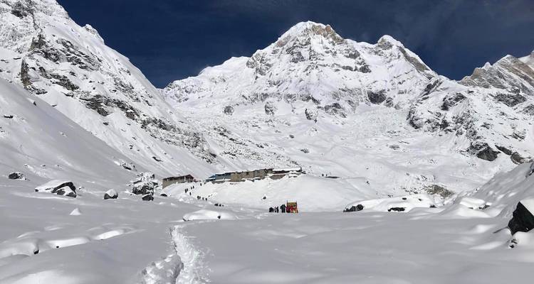 Snow-filled amphitheatre of Annapurna Base Camp with fresh footprints leading towards towering peaks.