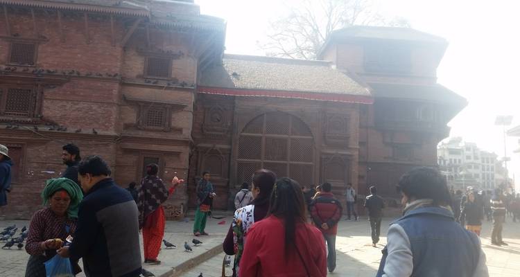Crowds wandering through a historic brick courtyard with traditional Newari architecture