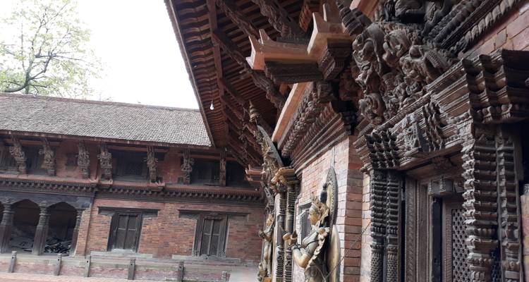 Detailed brick courtyard lined with ornate wooden carvings and overhanging pagoda roofs.