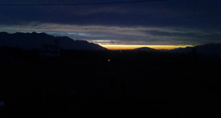 Dim dawn scene with mountains silhouetted against a narrow band of orange on the horizon