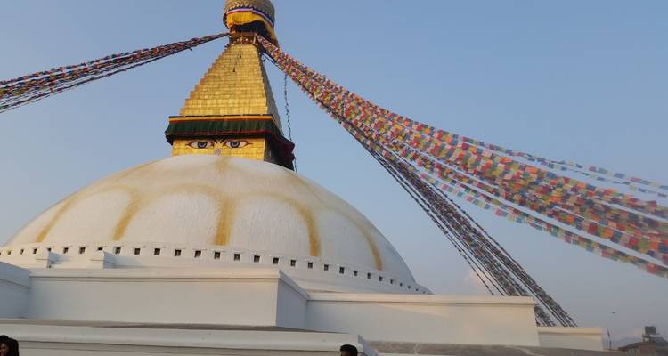 Golden hour light on the white dome and eyes of Boudhanath Stupa with streaming prayer flags