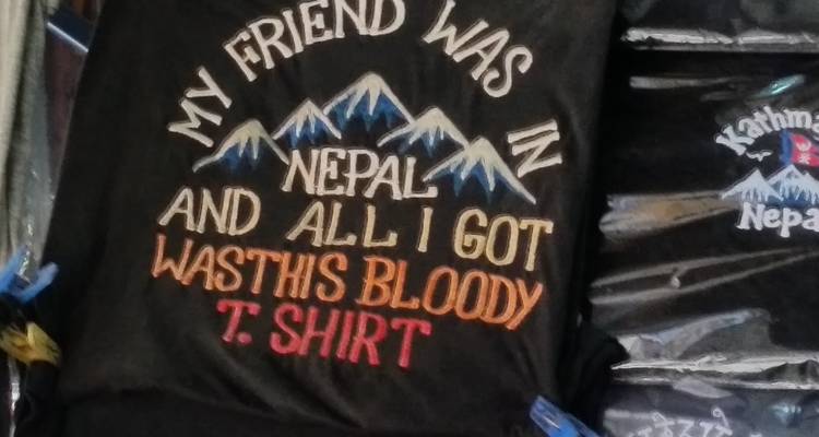 Souvenir T-shirt with humorous Nepal travel slogan hanging in a shop