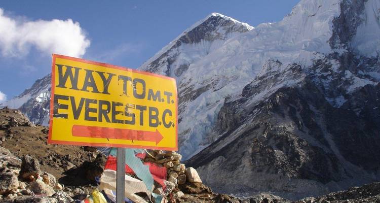 Bright yellow sign reading 'Way to Mt Everest B.C.' set against towering ice-covered cliffs