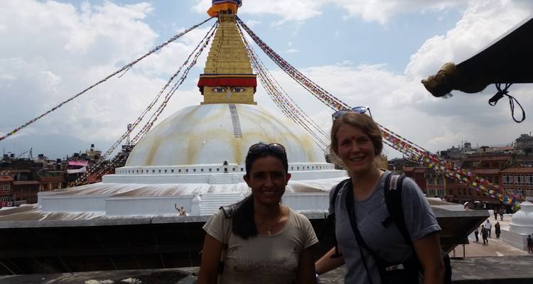 Deux femmes posant devant la Stupa de Boudhanath avec des drapeaux de prière s'étendant au-dessus d'elles