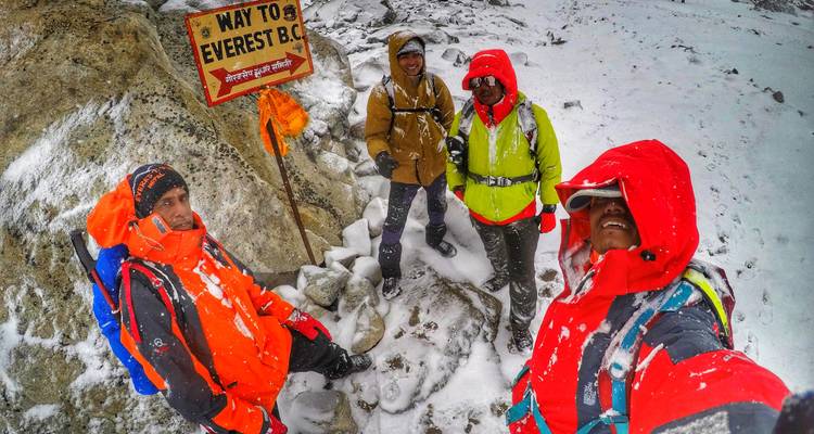 Randonneurs près d'un panneau indiquant le camp de base de l'Everest.