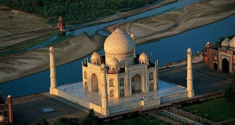 Luftaufnahme des Taj Mahal mit einem Fluss im Hintergrund.