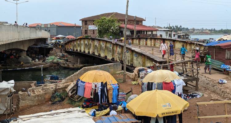 Un pequeño puente con puestos de mercado y algunas personas en el área circundante.