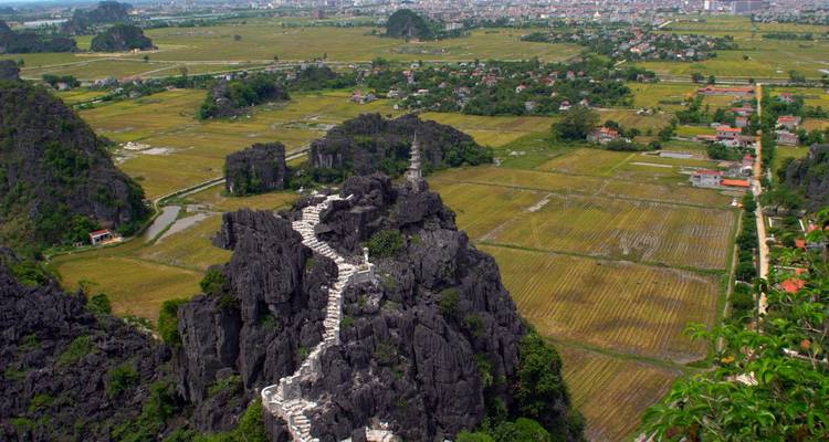 Un paisaje rocoso con montañas de piedra caliza y campos con vista de una escalera de dragón.