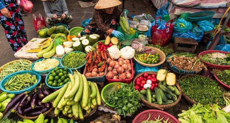 Escena vibrante de mercado con varias frutas y verduras expuestas para la venta.