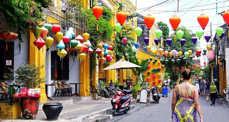 Bustling street with colorful lanterns in Hoi An with people and bicycles.