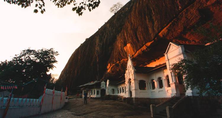Temple rupestre de Dambulla avec un arrière-plan rocheux au coucher du soleil.