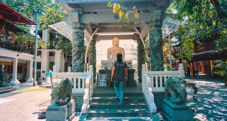 Personne debout devant une grande statue de Bouddha.