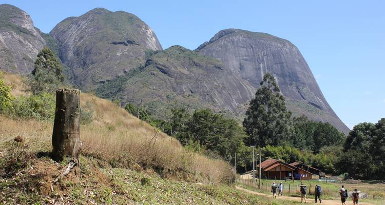 Wandelaars die lopen richting rotsachtige bergen in de verte.
