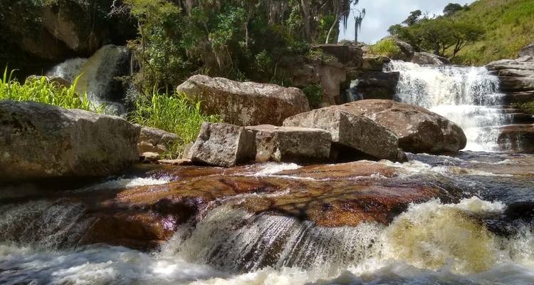 Waterval cascades en rotsen omlijst door bomen.