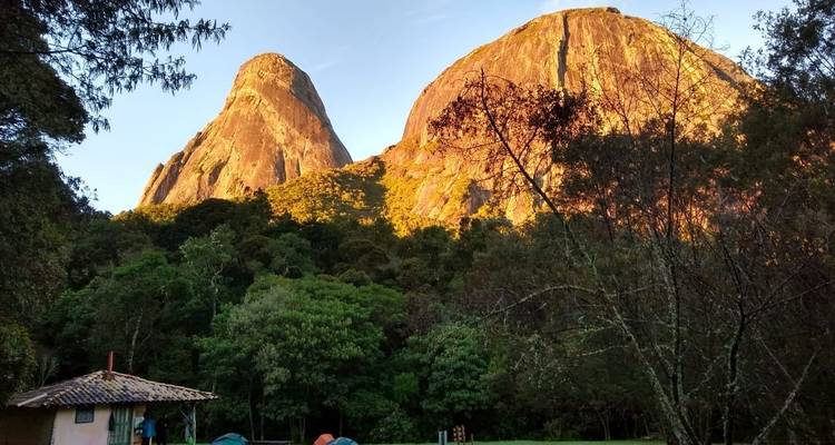"Gouden uur licht op rotsachtige toppen met bos eronder."