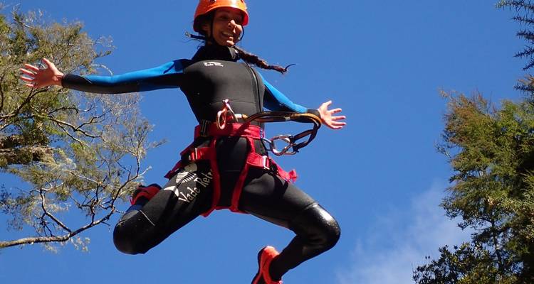 Eine Person in der Luft in einer Sprungpose in Outdoor-Ausrüstung.
