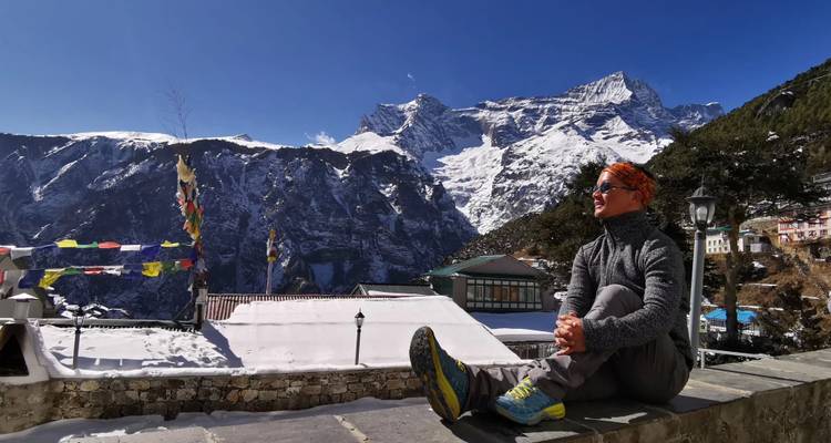 Person, die sitzt und eine Bergaussicht mit schneebedeckten Gipfeln genießt.