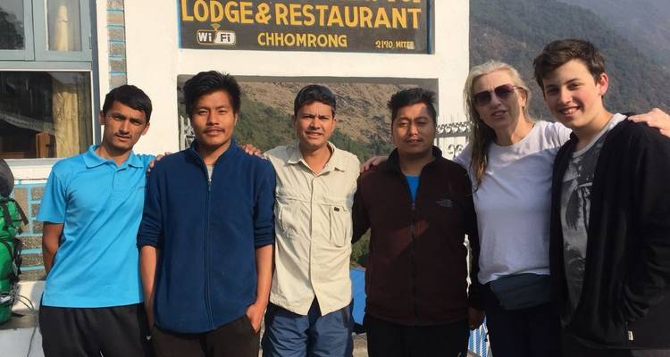 Group of people posing in front of a lodge with a mountain view.
