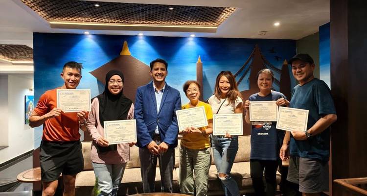 Des voyageurs présentant des certificats de réussite devant un mur coloré dans le salon d'un hôtel.