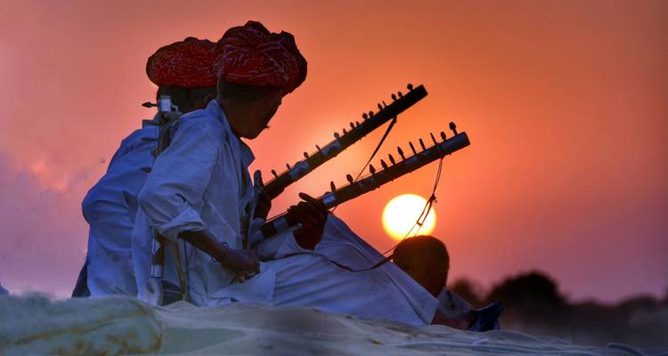 Silhouettes de musiciens avec des instruments traditionnels au coucher du soleil.