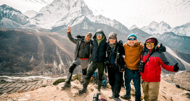 Group of hikers posing with mountains in the background.