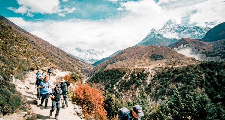 Hikers walking on a mountainous trail with scenic views.