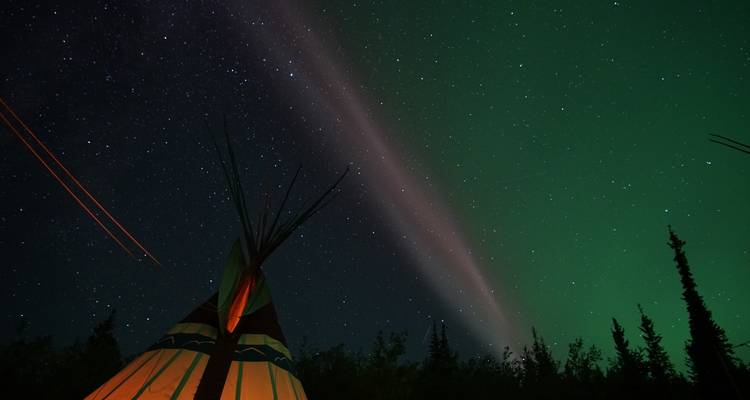 Una vista de la aurora boreal sobre un tipi bajo un cielo estrellado.