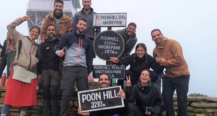 Groupe de personnes au point de vue de Poon Hill avec des panneaux indiquant l'altitude.