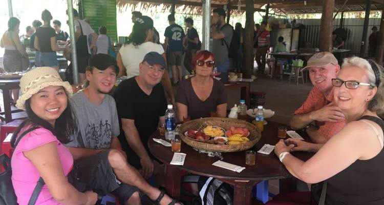 Eine Gruppe von Menschen, die mit einem Obstkorb auf dem Tisch speist.