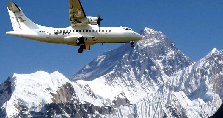 Avion volant au-dessus de montagnes enneigées sous un ciel dégagé.