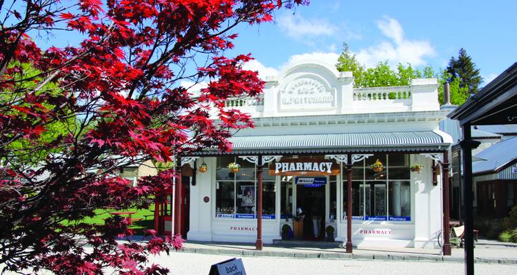 Historic white wooden pharmacy building in a quaint village street with red autumn leaves.