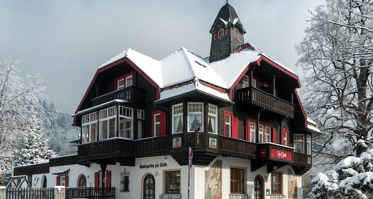 Traditioneel houten huis met besneeuwde dak en winterlandschap.