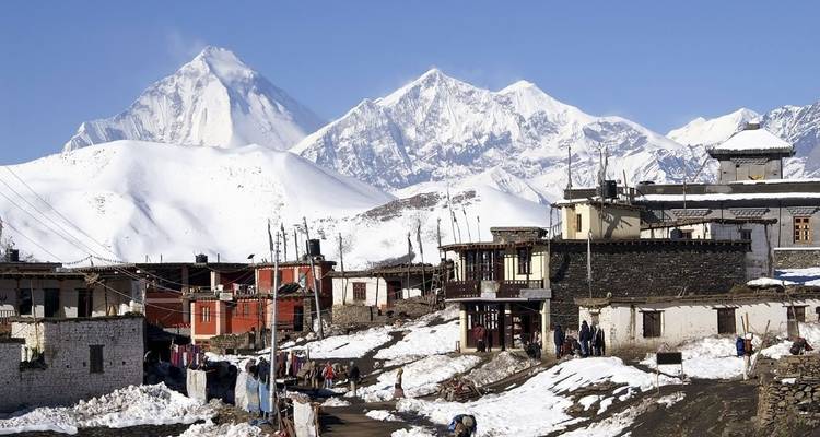 Pueblo nevado con montañas al fondo.